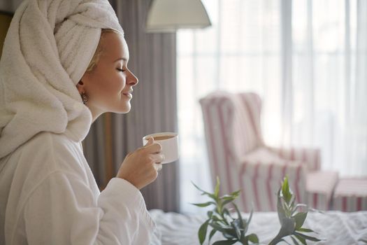 Beautiful Luxury Life. Breakfast. Happy Girl with a Cup of Coffee. Home Style Relaxation Woman Wearing Bathrobe and Towel after Shower. Spa Good Morning.