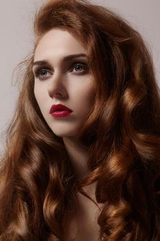 Beautiful ginger young woman with luxury hair style and fashion gloss makeup. Beauty portrait of sexy model with red hair. Long soft shiny hairstyle. Close-up studio shot of look redhead girl