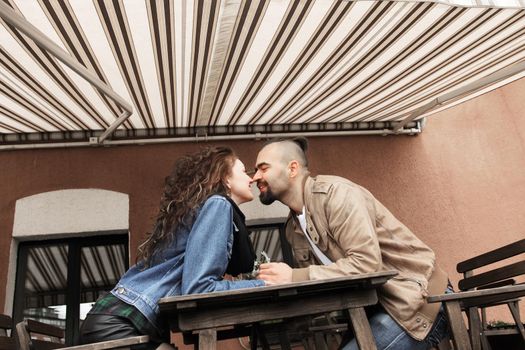 young couple kissing sitting at a table in a street cafe. love story