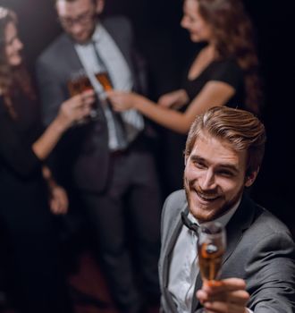 stylish young man standing with a glass of champagne.holidays and events