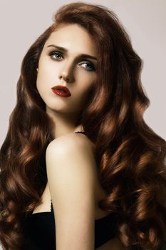 Beautiful ginger young woman with luxury hair style and fashion gloss makeup. Beauty portrait of sexy model with red hair. Long soft shiny hairstyle. Close-up studio shot of look redhead girl