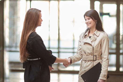 two businesswomen shaking hands in the office lobby. concept of partnership