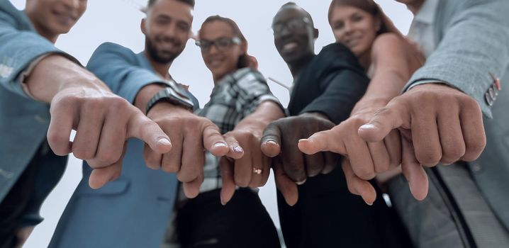 Beautiful business people are smiling, looking and pointing at camera, standing in office background