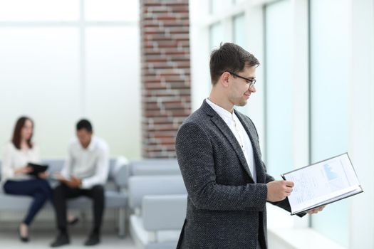 business man reading business documents standing in the office lobby. business concept