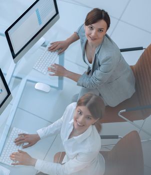 view from the top.two business women sitting at Desk and looking at camera.