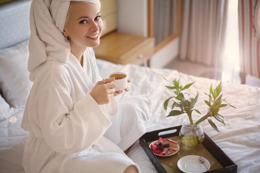 Beautiful Luxury Life. Breakfast. Happy Girl with a Cup of Coffee. Home Style Relaxation Woman Wearing Bathrobe and Towel after Shower. Spa Good Morning.