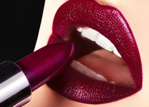 Close-up of woman's lips with fashion dark make-up. Trend Lips Makeup with bright dark Color Lipstick. Woman Applying Fashion lip Make-up. Macro shot of beautiful make up on full lips. Choice lipstick