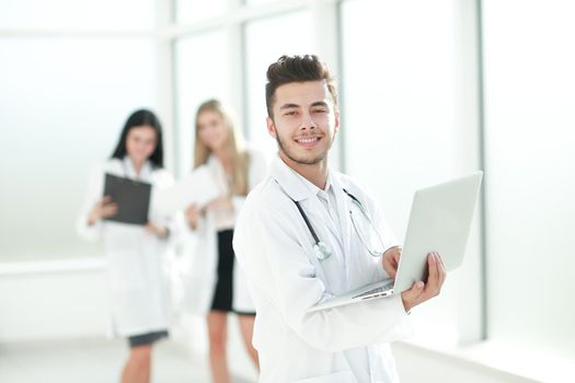 doctor therapist uses a laptop while standing in the hallway of the clinic. photo with copy space