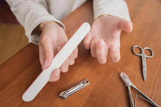 Close-up of hand of caucasian young woman doing manicure at home with nail supplies