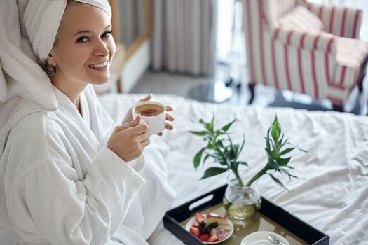 Beautiful Luxury Life. Breakfast. Happy Girl with a Cup of Coffee. Home Style Relaxation Woman Wearing Bathrobe and Towel after Shower. Spa Good Morning.