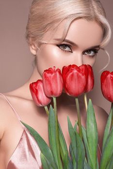 Beautiful sexy Blonde Woman with luxury retro Make-up. Girl with Spring Flowers Bouquet on Beige Background for any Celebrating. Fresh Style for Womans Day or Valentines