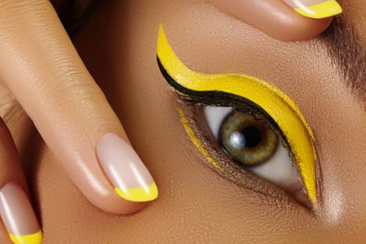 Beautiful macro close-up of female Eye with bright yellow Eyeliner Makeup. Neon Disco make-up and Fashion Manicure. Summer beauty styleCloseup macro shot of fashion liner eyes visage
