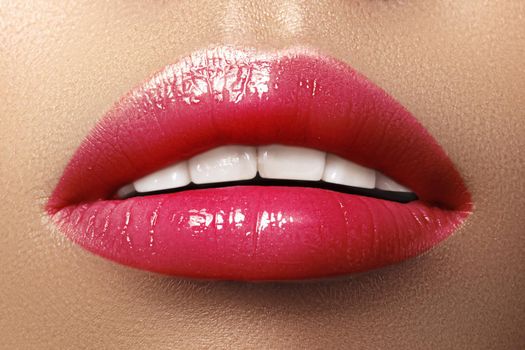 Close-up macro shot of female mouth. Sexy Glamour red lips Makeup with sensuality gesture. Magenta gloss lipstick. Full lips