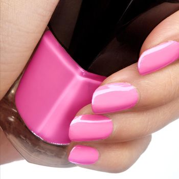 Manicured nails with bright nail polish. Manicure with pink nailpolish. Fashion manicure. Shiny gel lacquer in bottle.