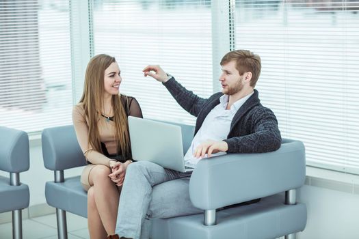 members of the business team with a laptop, discussing work problems sitting on the office sofa in the lobby of the office