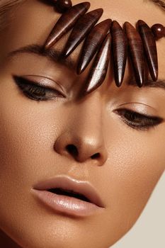 Close-up face of beautiful young woman with smooth tanned skin. Portrait of beauty model with natural bronze make-up. Spa, skincare and wellness