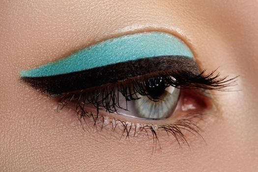 Beautiful macro shot of female eye with makeup. Perfect shape of eyebrows, blue eyeliner. Cosmetics and make-up.