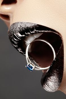 Close-up of beautiful woman's Lips with bright Fashion Make-up. Macro black and silver lip gloss. Luxury Jewelry accessorie.