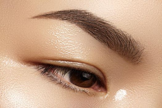 Beautiful macro of female eye with classic clean makeup. Perfect shape eyebrows, beige eyeshadows. Cosmetics and make-up. Care about eyes. Asian eye with daily make-up