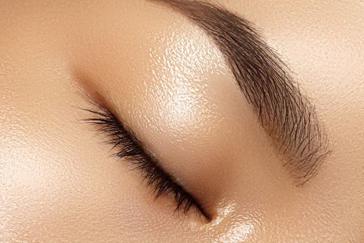 Beautiful macro of female eye with classic clean makeup. Perfect shape eyebrows, beige eyeshadows. Cosmetics and make-up. Care about eyes. Asian eye with daily make-up