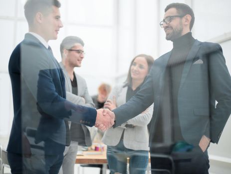 through the glass. business people shaking hands with each other. business concept