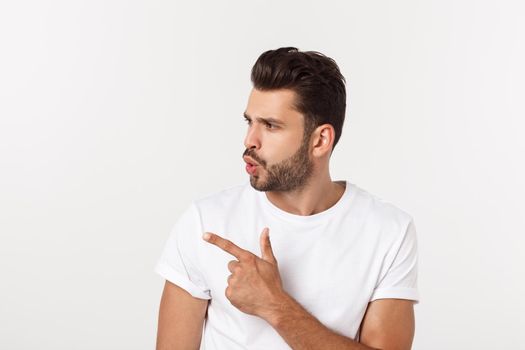 Smiling young man pointing finger against a white background