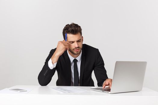 Serious handsome businessman working in the office,front view with laptop, isolated on white