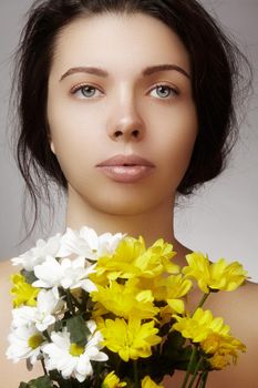 Beautiful young woman with perfect clean shiny skin, natural fashion makeup with spring flowers. Close-up woman, fresh spa look.