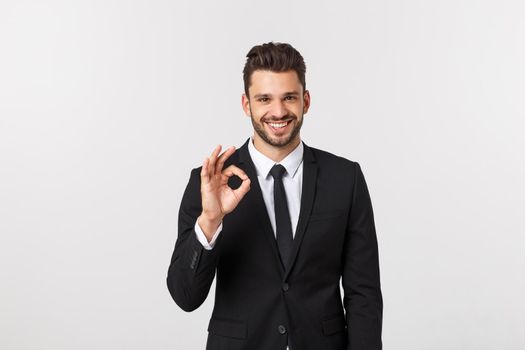 Handsome smiling businessman showing ok sign with fingers over gray background