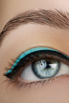 Beautiful macro shot of female eye with makeup. Perfect shape of eyebrows, blue eyeliner. Cosmetics and make-up.