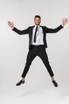 Portrait of a happy businessman jumping in air against isolated white background