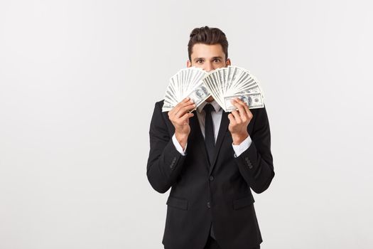 Portrait of a satisfied young businessman holding bunch of money banknotes isolated over white background