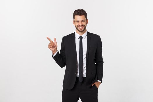 Portrait of young business man in suit pointing at copy space over white background