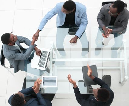 top view. business partners shaking hands during negotiations in the office