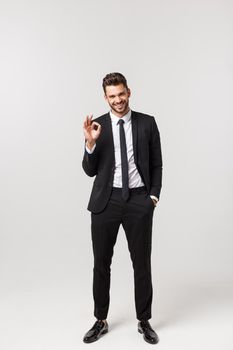 Full length of happy employee showing okay sign hand gesture isolated on white background.