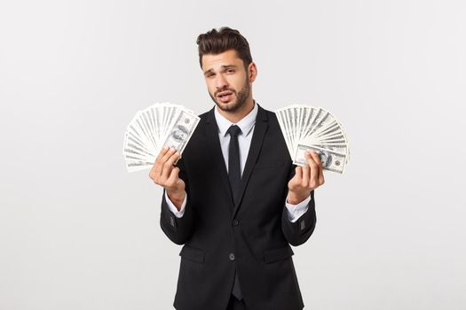 Portrait of a satisfied young businessman holding bunch of money banknotes isolated over white background