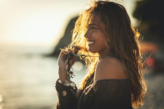 A beautiful young woman is having fun and relaxing on the beach at the sunset. 