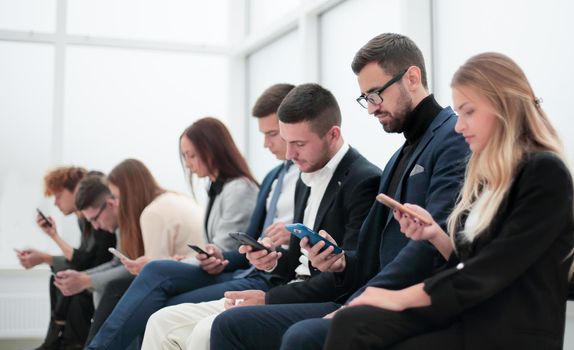 group of young business people with smartphones sitting in a row. photo with copy space