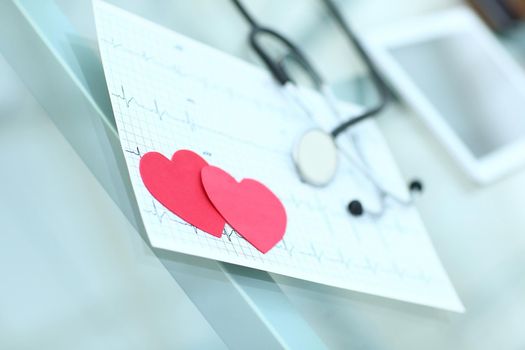 stethoscope,cardiogram and two red paper heart on the table.the concept of health