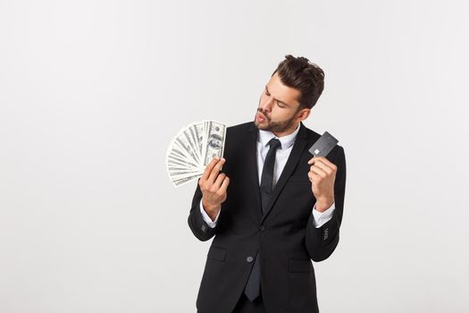 Portrait of a happy smiling man holding bunch of money banknotes and showing credit card isolated over white background