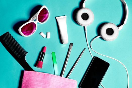 Above view of woman bag stuff . Set of female cosmetics and accessories. Glamour tools and beauty objects. Pink bag, white headphones, sunglasses and smartphone