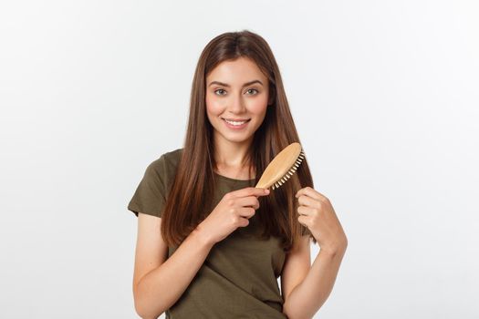 Happy young woman combing her long healthy hair on white background