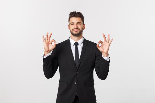 Handsome smiling businessman showing ok sign with fingers over gray background