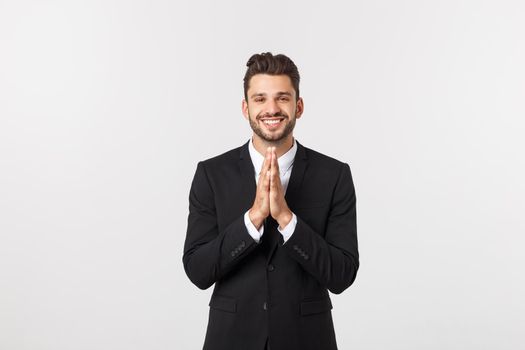 Handsome young business man standing praying, isolated over white background. Concept of idea, ask question, think up, choose, decide,