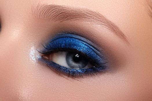 Closeup Macro of Woman Face with Blue Eyes Make-up. Fashion Celebrate Makeup, Glowy Clean Skin, perfect Shapes of Brows. Shiny Shimmer