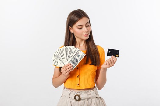 Photo of happy young woman standing isolated over grey background. Looking aside holding money and credit card.