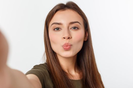 Portrait of a smiling cute woman making selfie photo on smartphone isolated on a white background