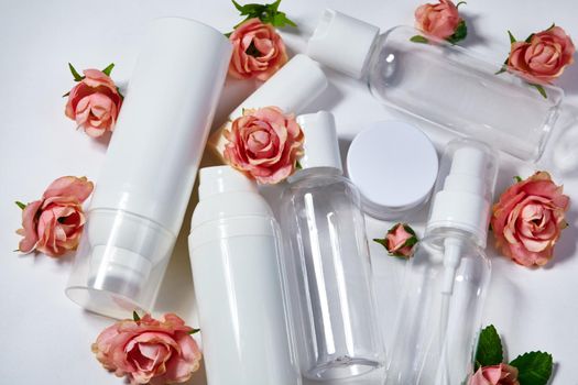 White cosmetic bottles on white background. Wellness, spa and body care bottles collection with spring parfume flowers. Beauty treatment, bathroom set.