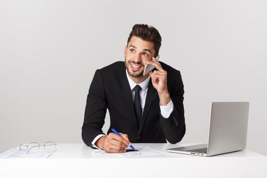Young businessman in a workplace keeping a conversation with the mobile phone