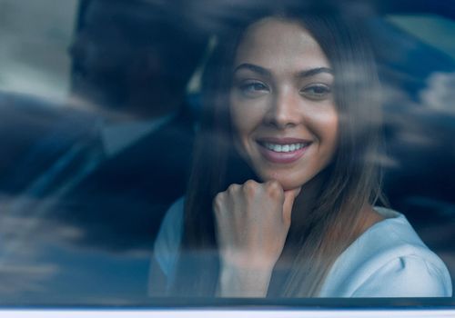 woman sitting in a moving car, looking through her window towards